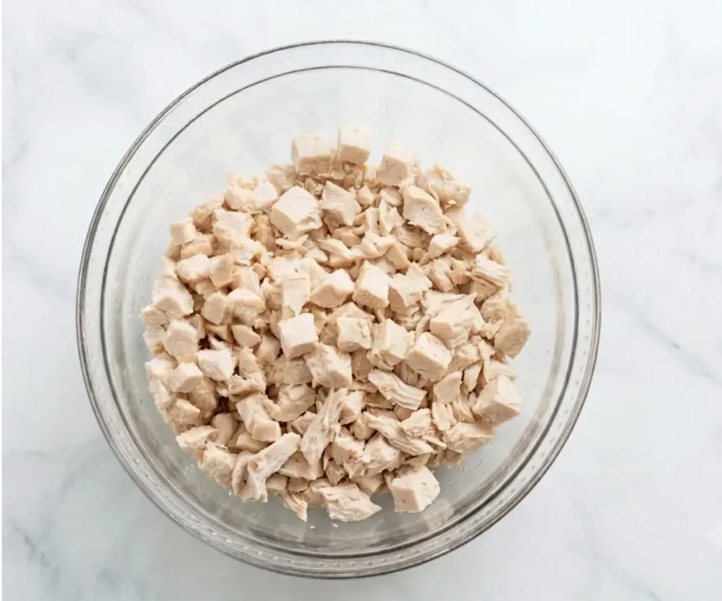 Diced cooked chicken breast in a glass mixing bowl